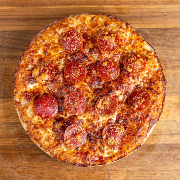 Round pepperoni pizza with melted cheese on a wooden table, viewed from above.