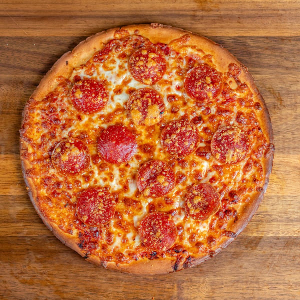 Whole pepperoni pizza with melted cheese and golden crust on a wooden table.